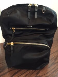 Photo of a black backpack sitting on a wooden table.