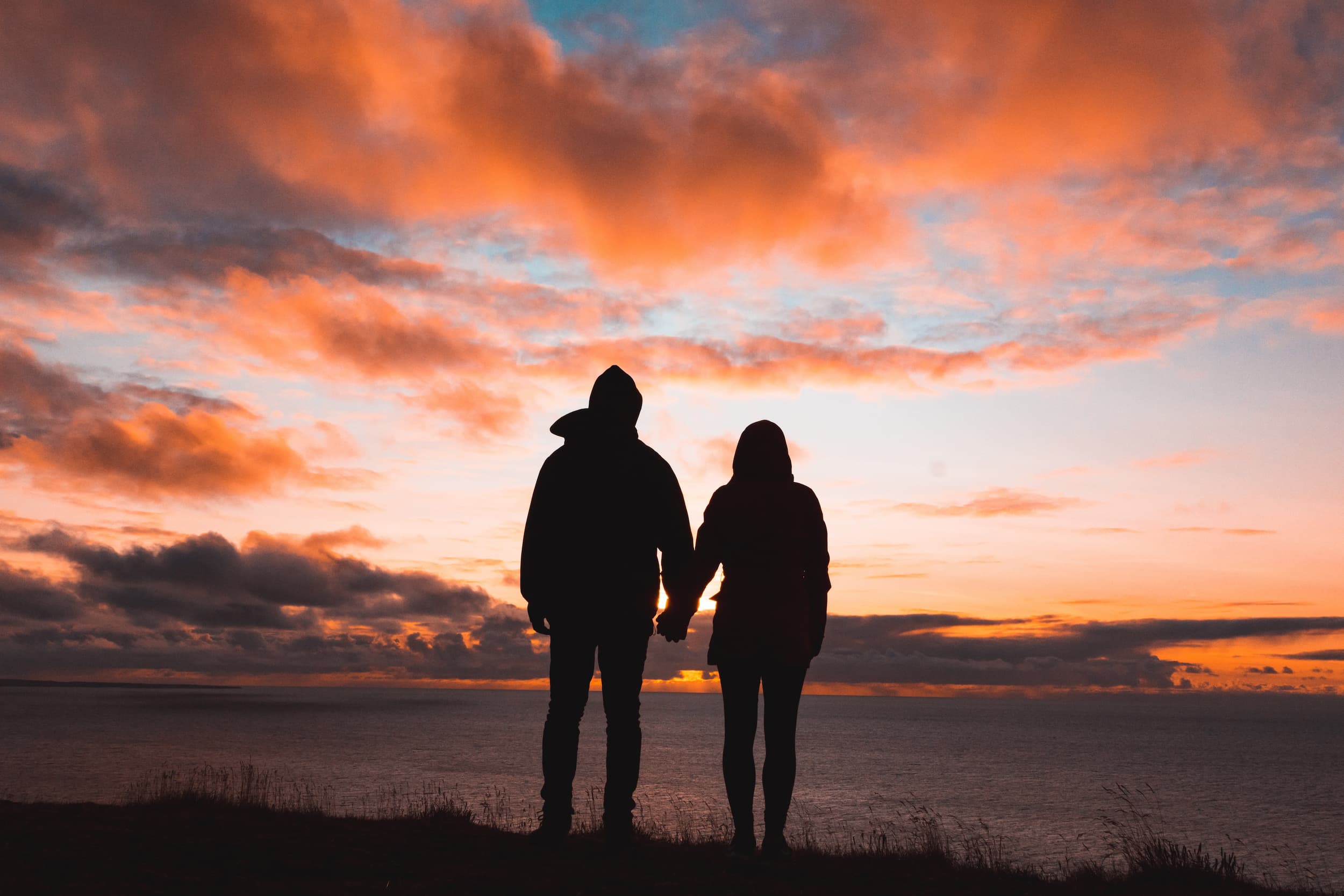 Couple holding hands in front of sunset