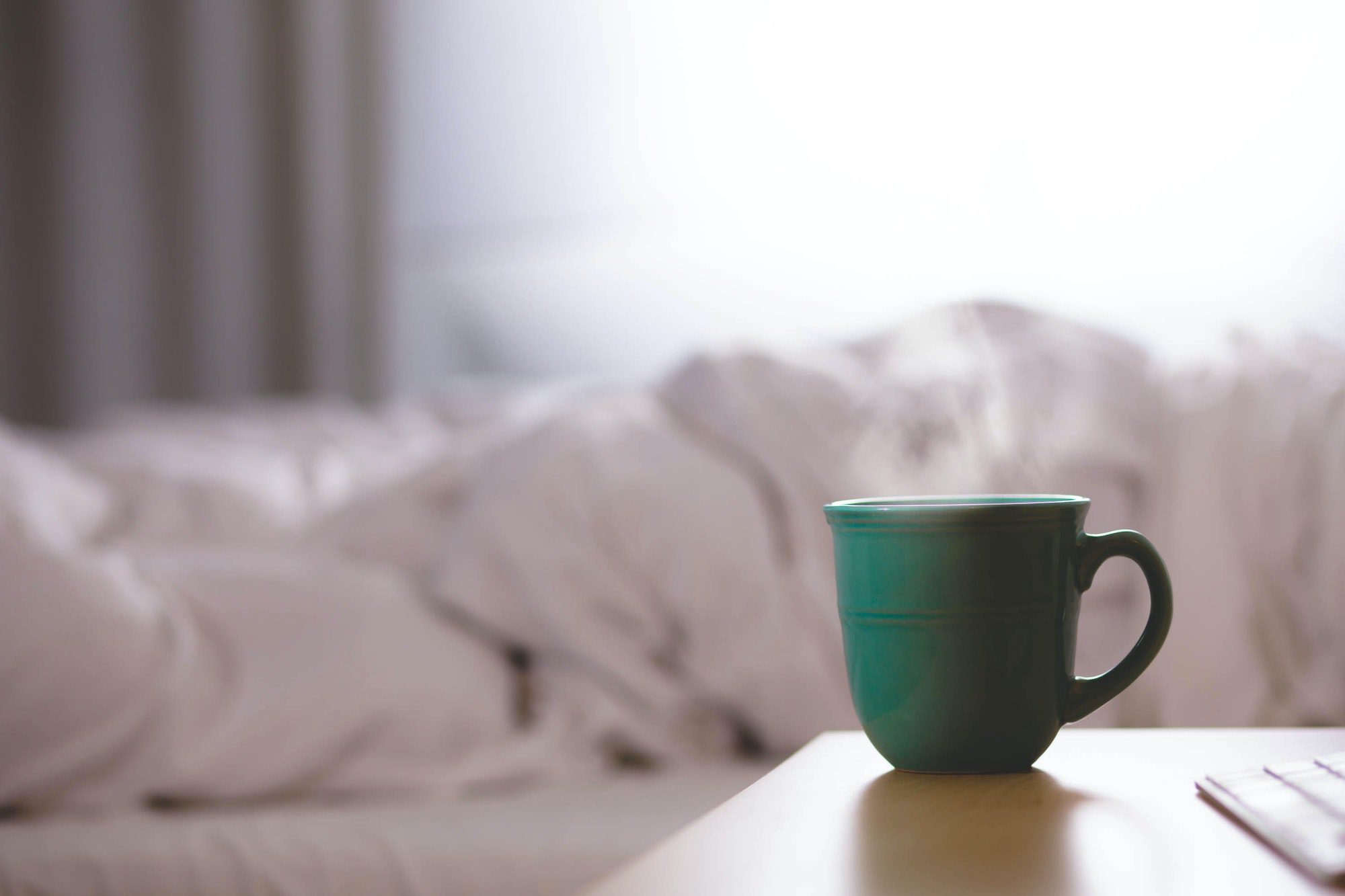 Hot cup of coffee near a bed