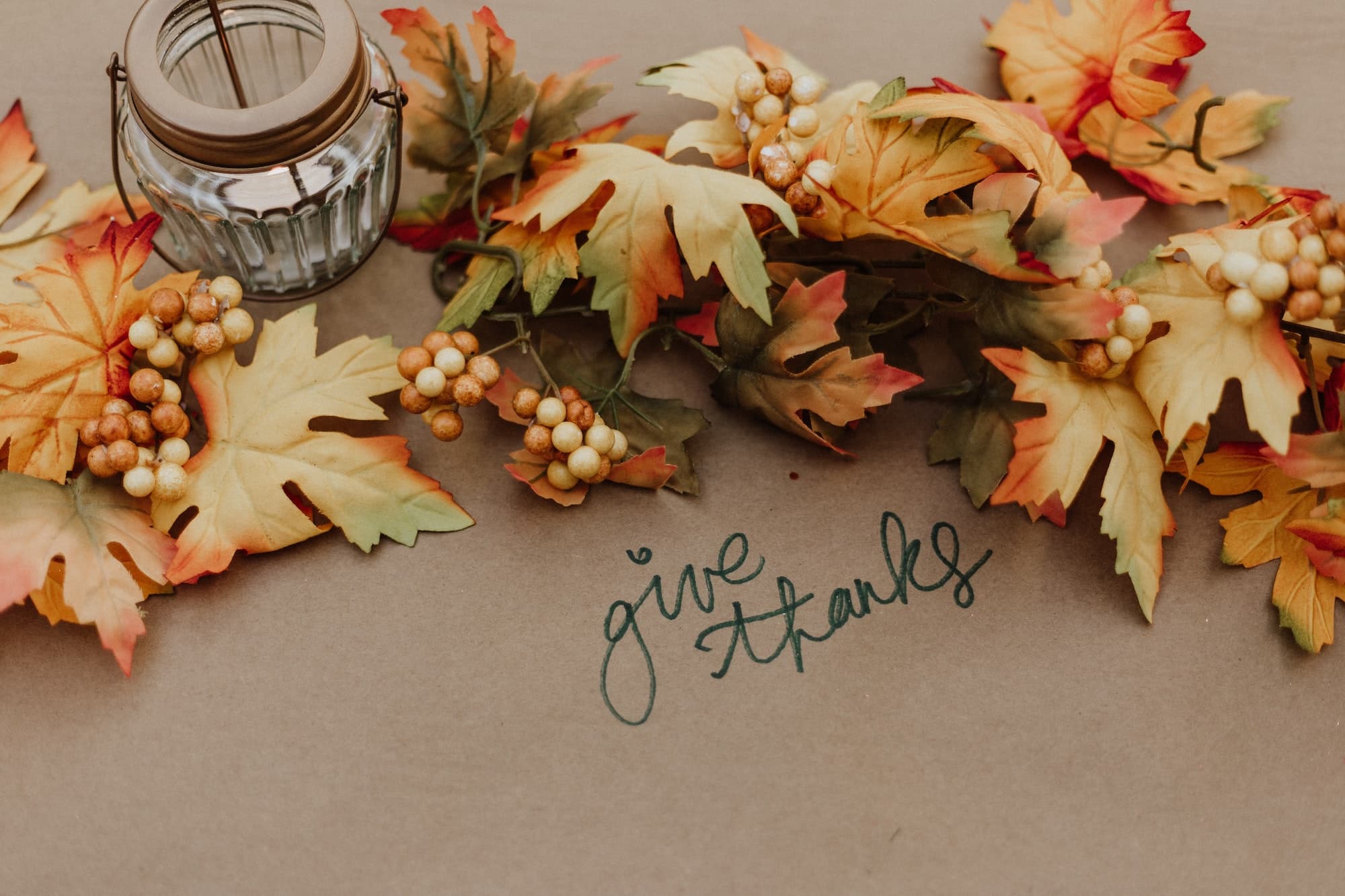 Give thanks writing on kraft paper with some fall leaves on a table
