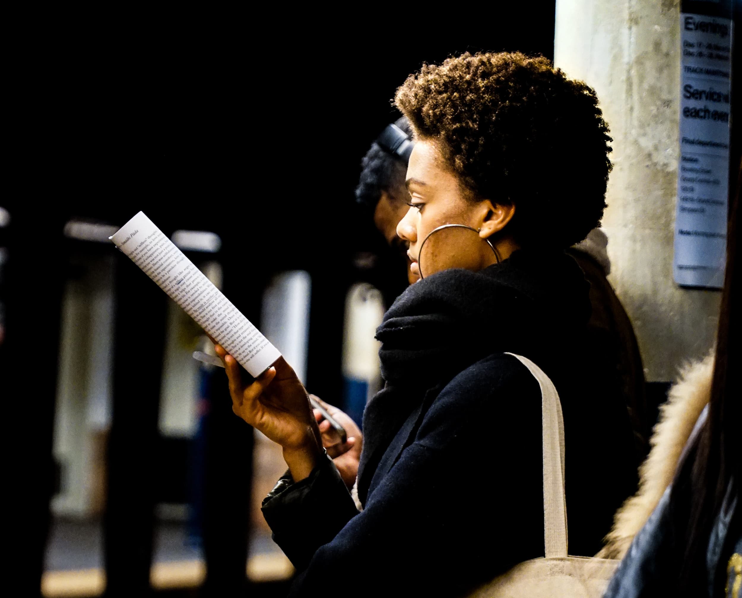 Woman reading a book waiting for public transit