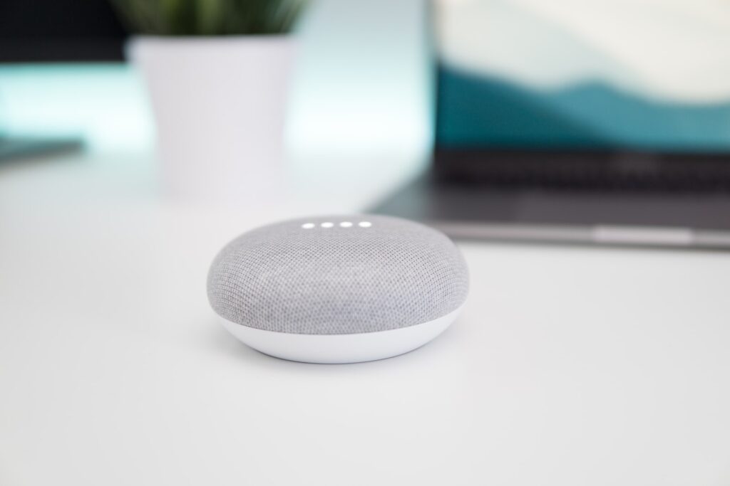 turned on gray and white Google Home Mini speaker on white surface