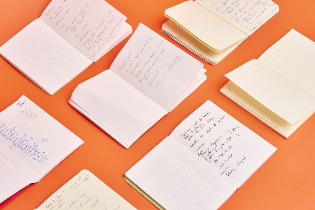 Flat lay of Gretchen's open notebooks on orange background