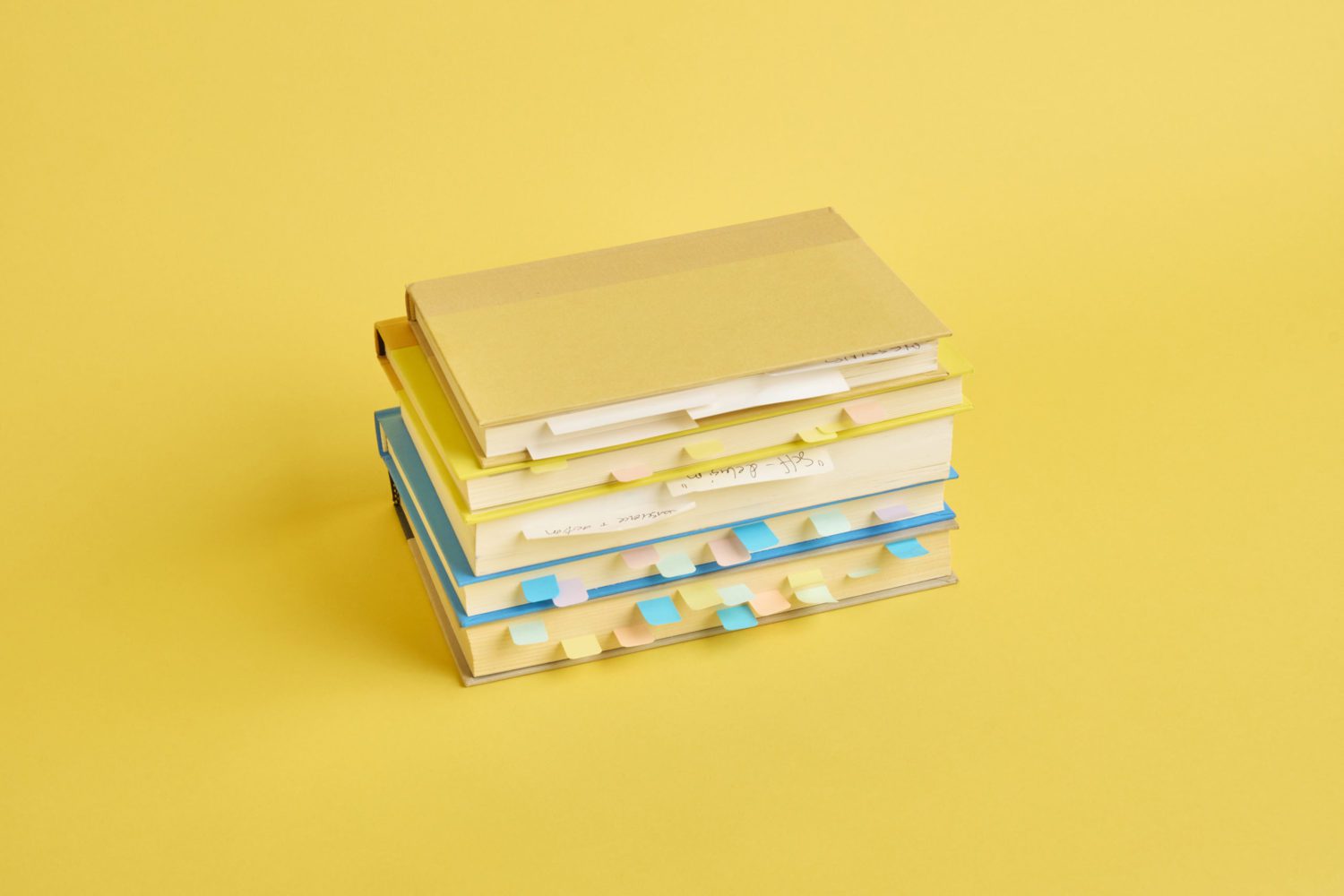 Stack of books with page markers on yellow background
