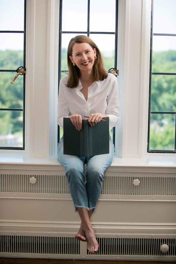 Gretchen holding a book on a window sill