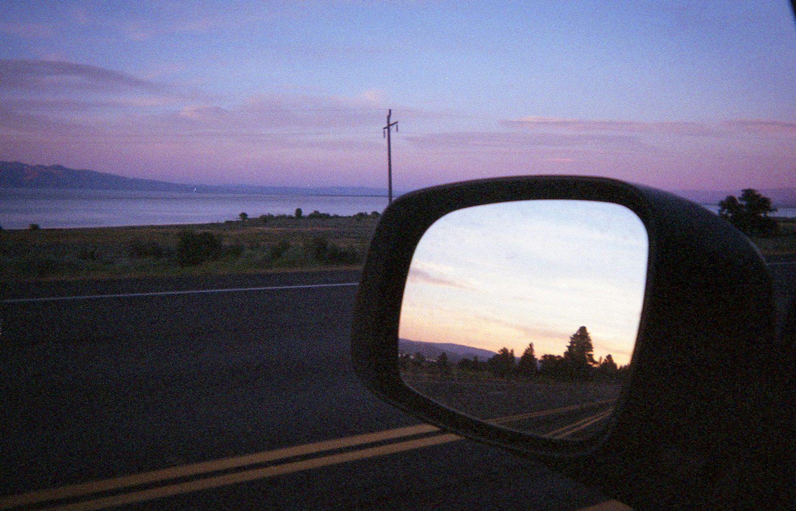 a rear view mirror of a car on a road