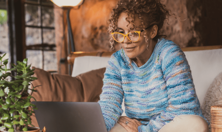 Woman sitting on couch engaged in a conversation on her laptop.