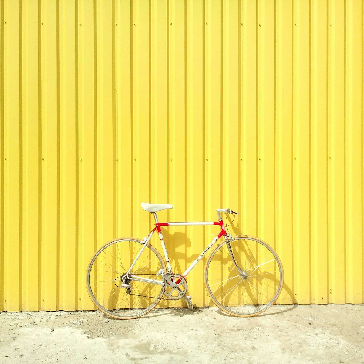 white and red hardtail bike on yellow wall