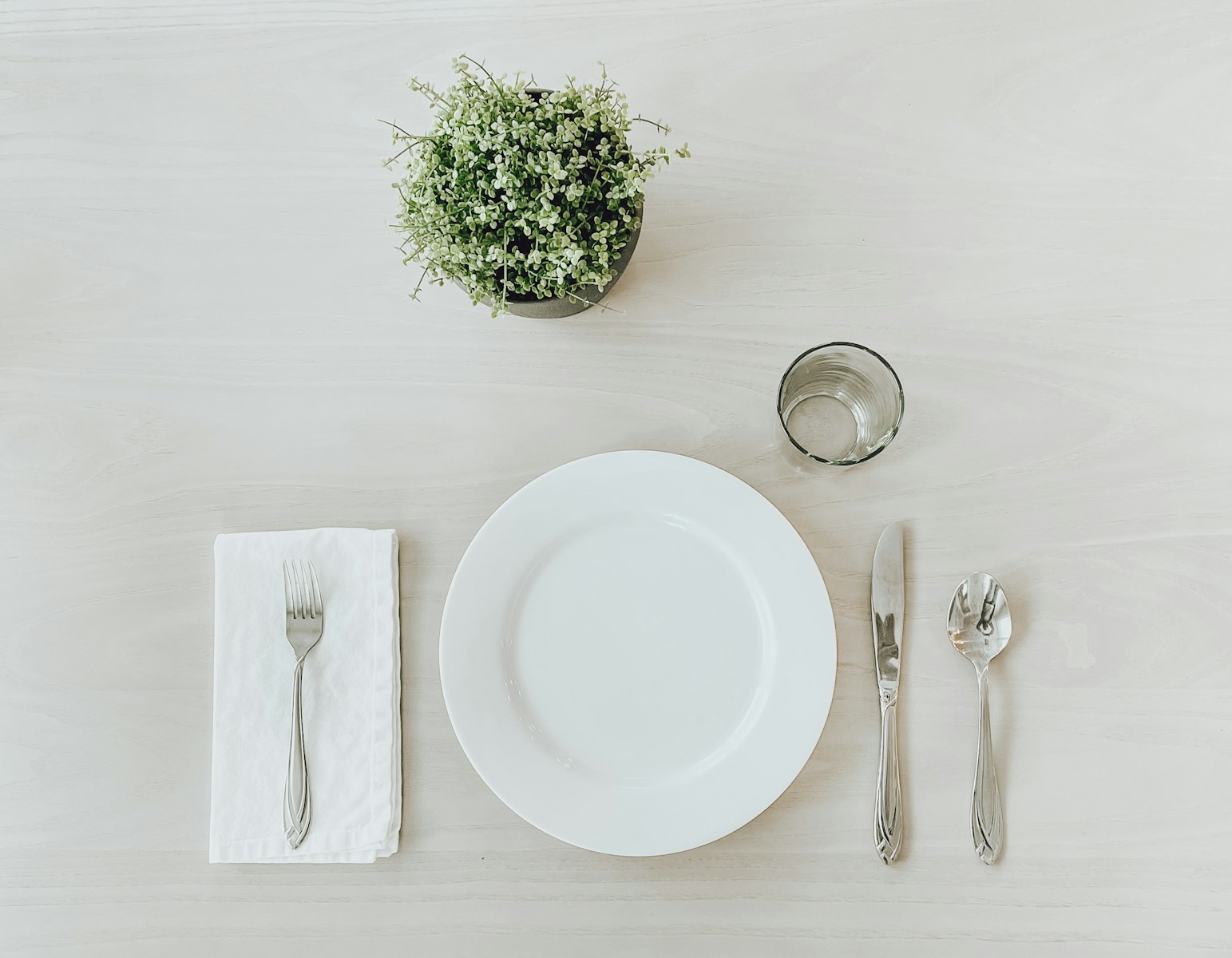 white ceramic plate beside stainless steel fork and bread knife on white table