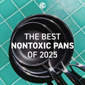 Headline: "The best nontoxic pans of 2025." A topdown view of a set of pans stacked on a green tile surface.