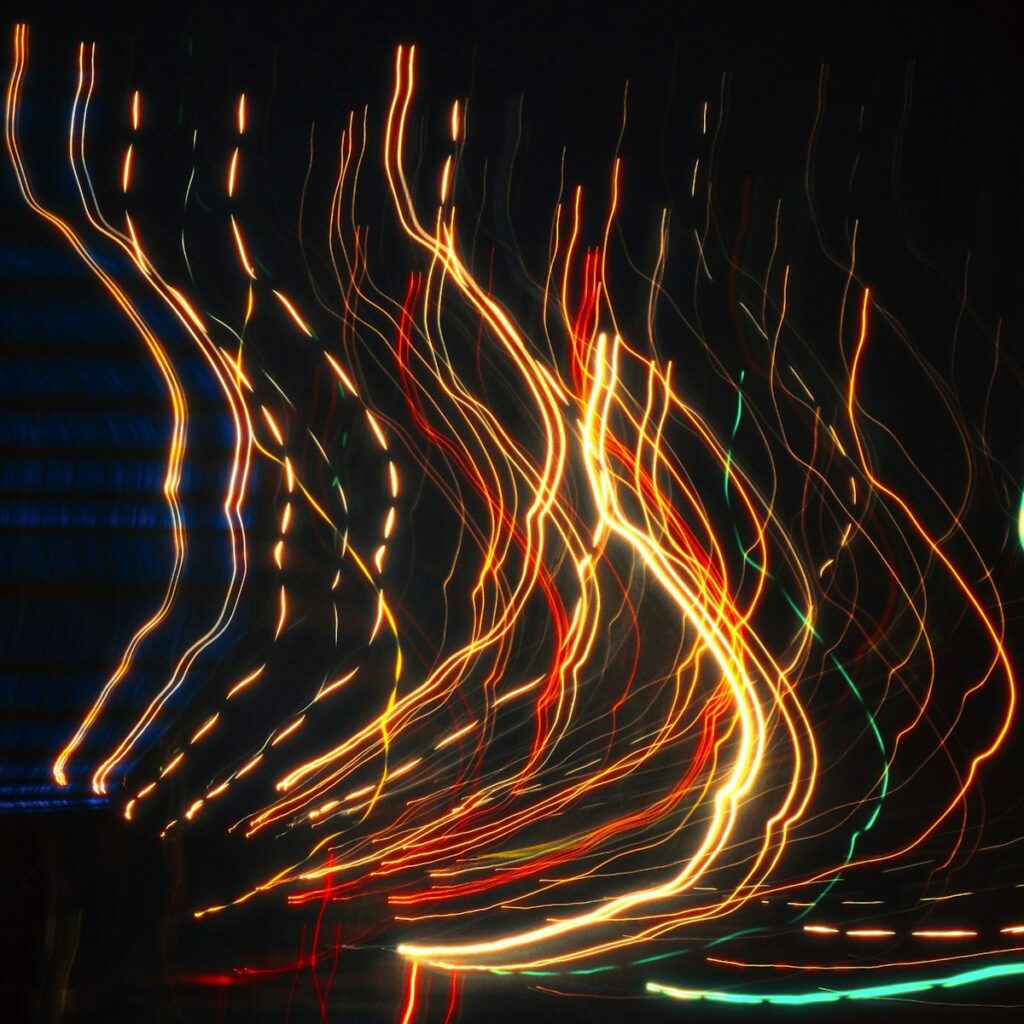 Light trails create abstract patterns against black.