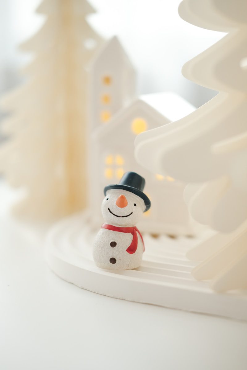 A snowman figurine sitting in front of a christmas tree