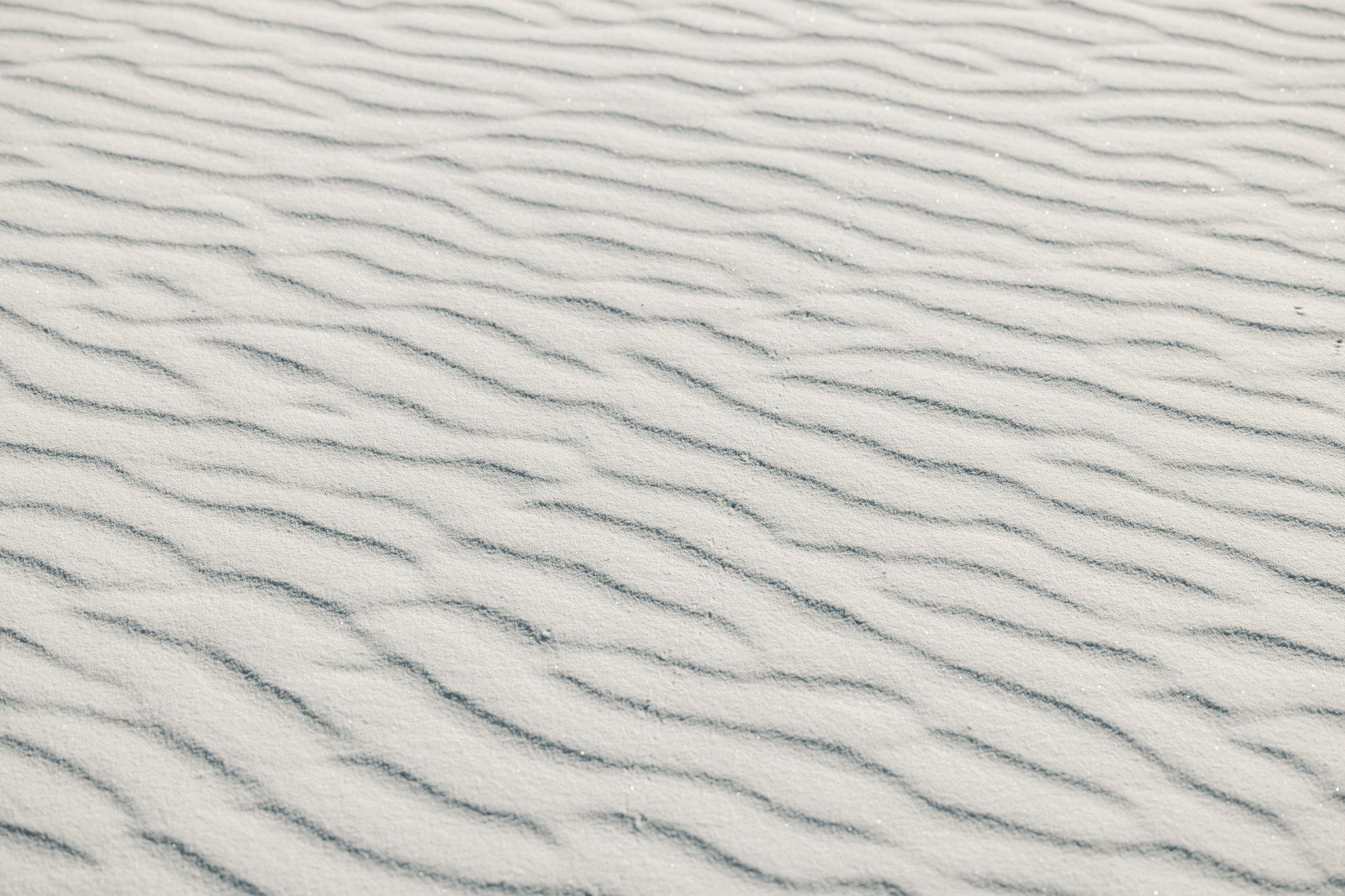 Rippled white sand dunes with subtle grey lines