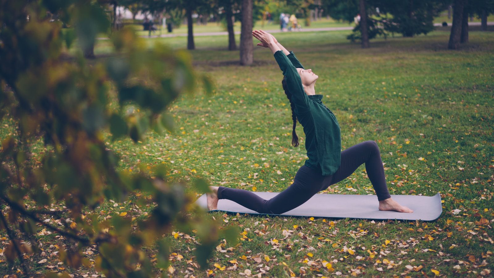 Woman stretching on yoga mat in autumn park