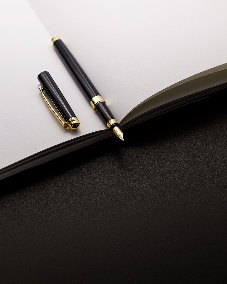 A black and gold pen rests on an open notebook.