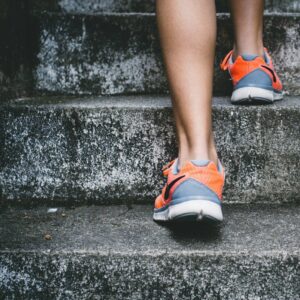 person wearing orange and gray Nike shoes walking on gray concrete stairs