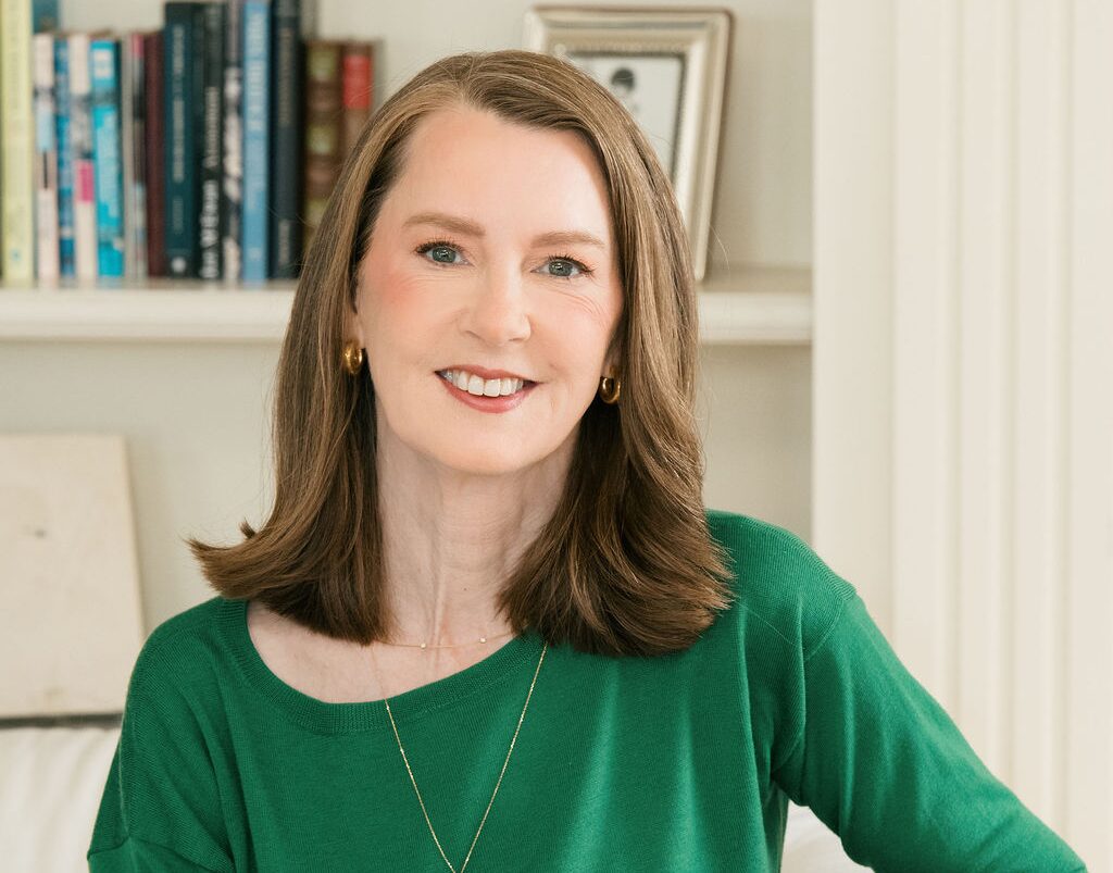 Photo of Gretchen Rubin wearing a green shirt, sitting in front of a bookshelf.