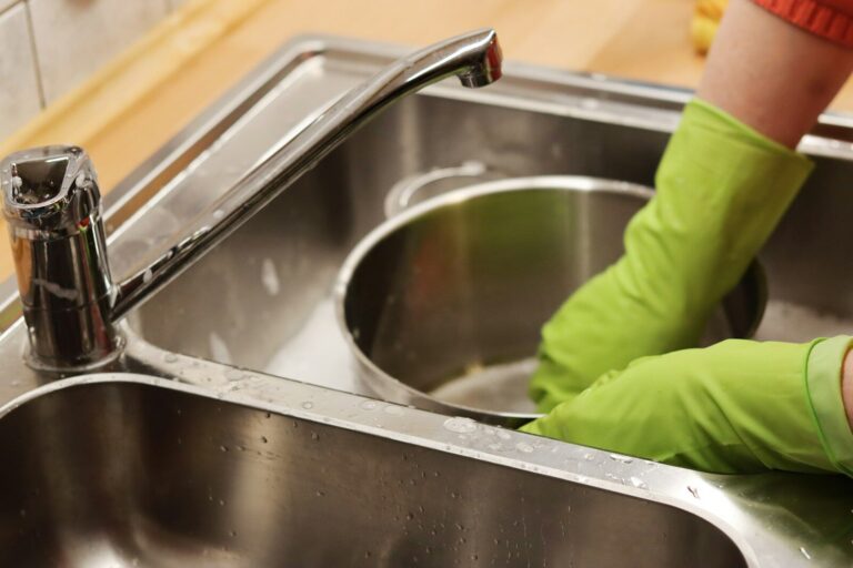 close up of hands washing dishes in a sink