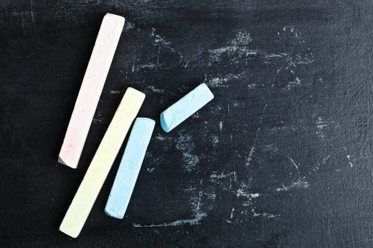 A chalkboard with three erasers on top of it