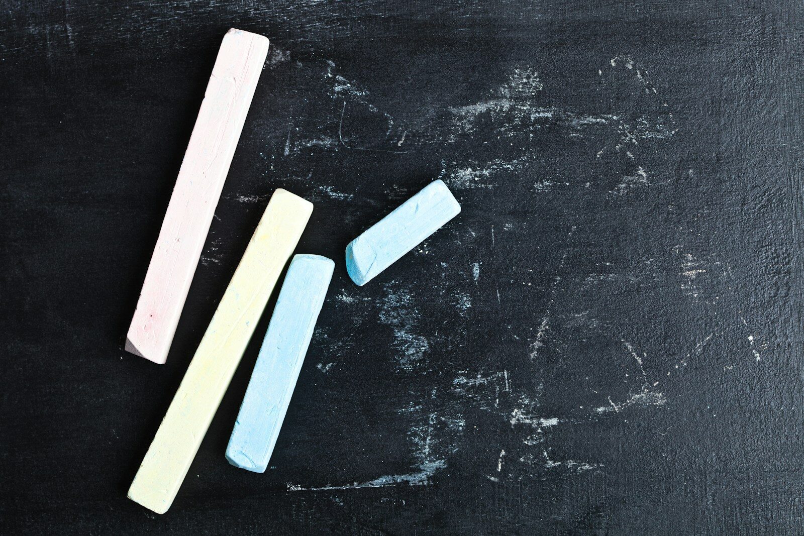 A chalkboard with three erasers on top of it