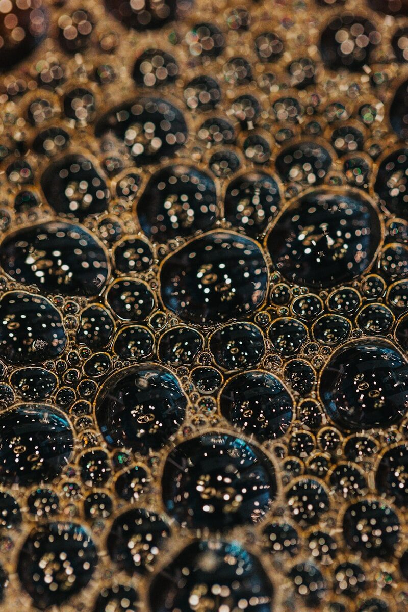 Dark bubbles with golden reflections on a liquid surface.
