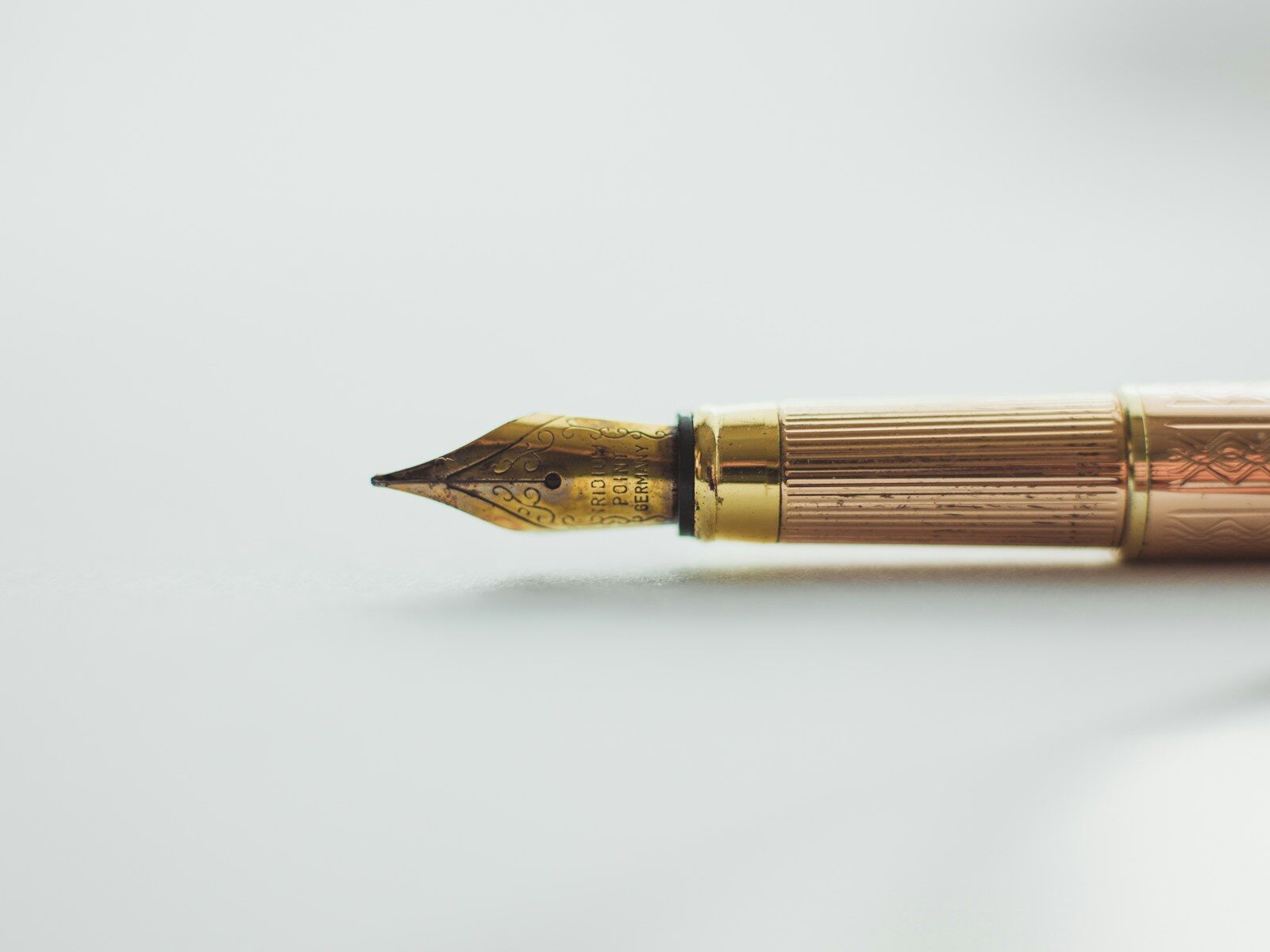 A gold fountain pen with an engraved nib on a white surface